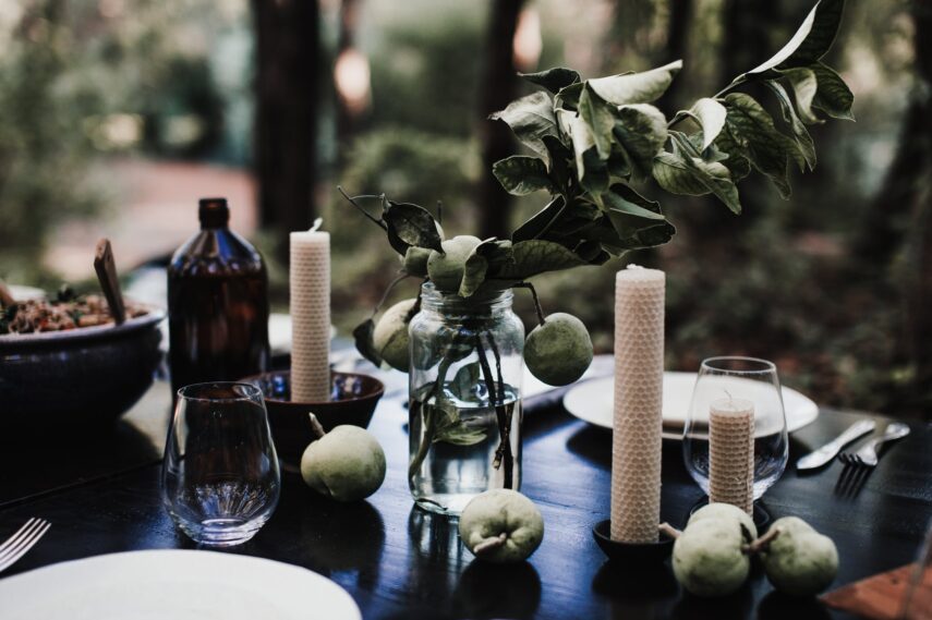 Esstisch dekorieren: Kerzen und Pflanzen auf einem dunklen Tisch.