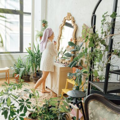 Welche Pflanzen vertragen viel Sonne: Frau steht im Zimmer mit vielen Pflanzen