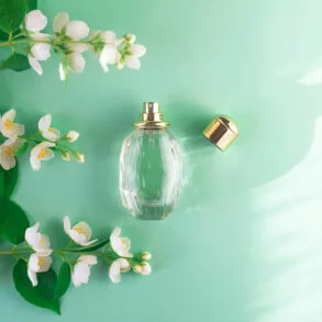 Jasmin Parfum: Parfumflasche neben frischen Jasminblüten