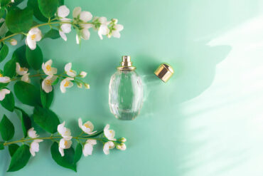 Jasmin Parfum: Parfumflasche neben frischen Jasminblüten