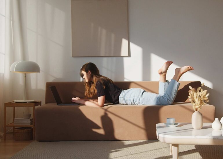 Scandi Style Wohnzimmer: Frau sitzt auf einer braunen Couch