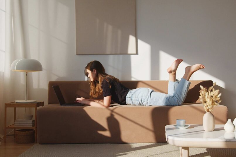 Scandi Style Wohnzimmer: Frau sitzt auf einer braunen Couch