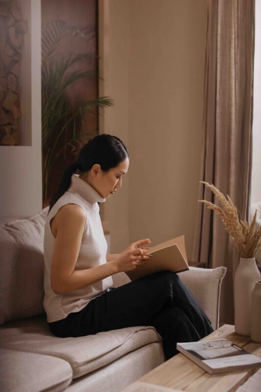 Scandi Style Wohnzimmer: Frau sitzt auf der beigen Couch und liest