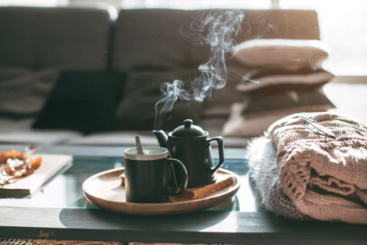 Hygge-Einrichtung: Couchtisch mit dampfendem Tee und gemütlichen Decken